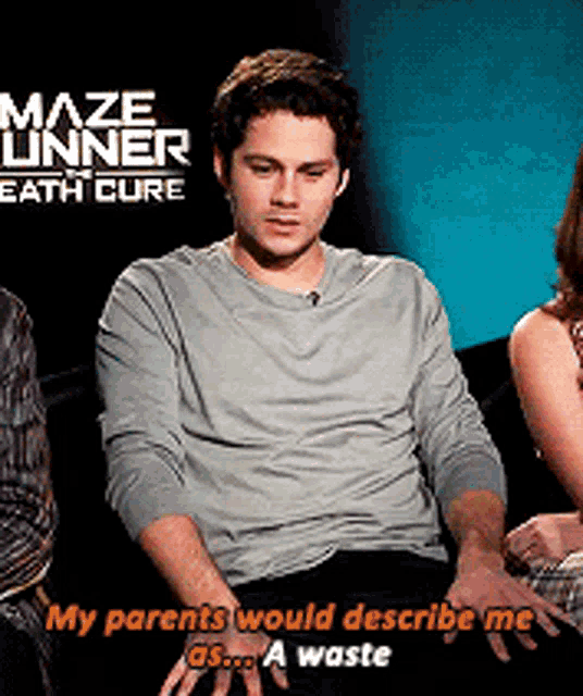 a man sitting in front of a sign that says maze runner