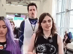 a man and two women are walking in a hallway .