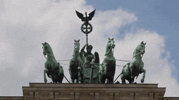a statue on top of a building with horses pulling a carriage