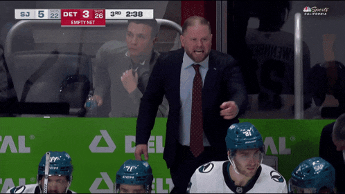 a man in a suit and tie stands in front of empty net