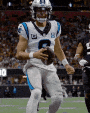 a man in a carolina panthers uniform holds a football
