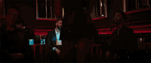 two men in suits sit at a table with glasses of wine