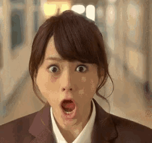 a woman in a suit and white shirt is making a surprised face with her mouth open .