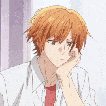 a man with orange hair and a red shirt is sitting with his hand on his chin