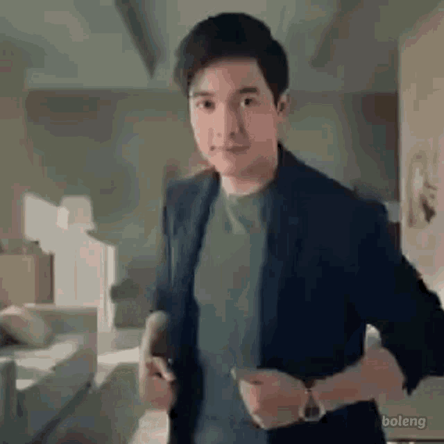 a man in a suit is standing in a living room and looking at the camera .