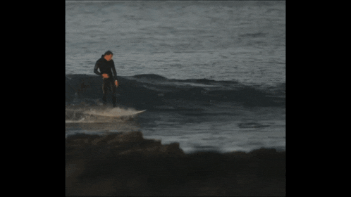 a man in a wet suit is riding a wave on a surfboard in the ocean