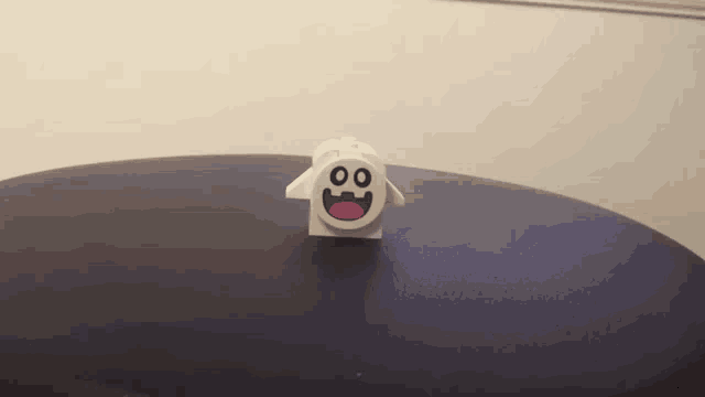 a lego ghost with a smiley face is sitting on top of a table .