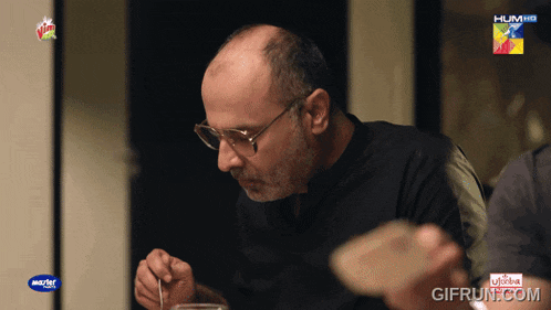 a man eating a meal with a hum hd advertisement behind him