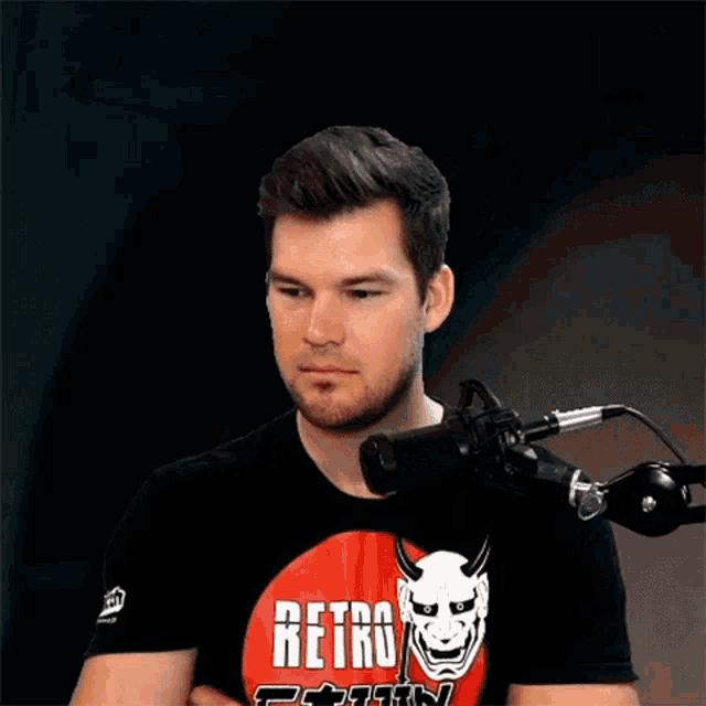 a man wearing a red retro shirt is screaming into a microphone