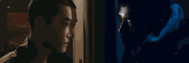 two young men are looking at each other in the dark .