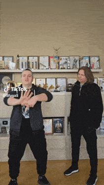 a man and a boy are dancing in front of a shelf full of trophies and awards