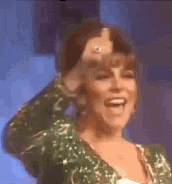 a woman in a green dress is giving a thumbs up sign .