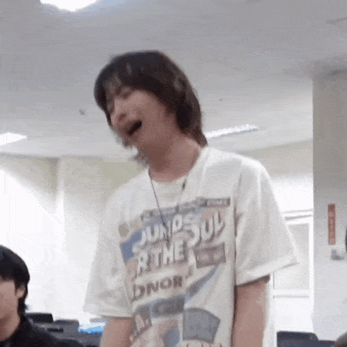 a man wearing a white t-shirt with a necklace around his neck is yawning in a room .