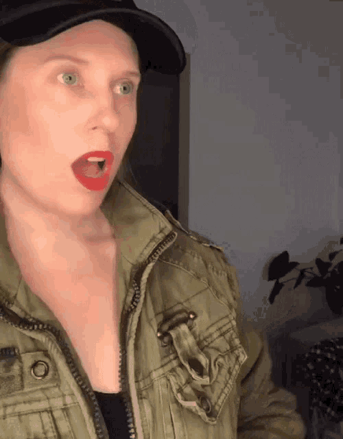 a woman wearing a black hat and a green jacket has her mouth open