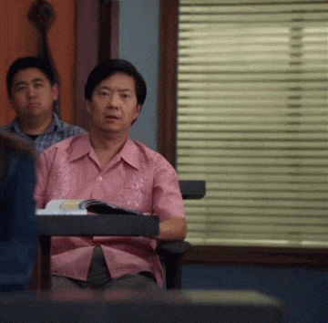 a man in a pink shirt is sitting at a desk