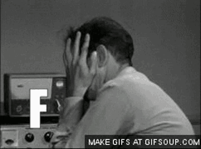 a black and white photo of a man covering his face with the letter f behind him