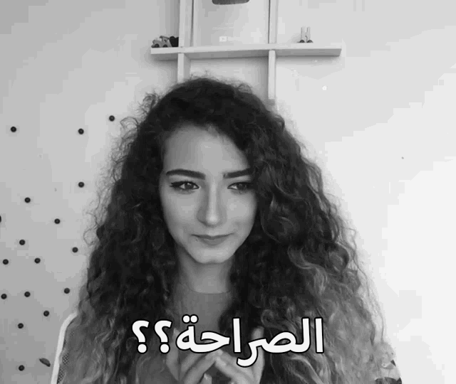 a woman with curly hair stands in front of a shelf with a youtube logo on it