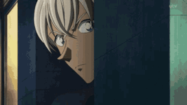 a man with blonde hair and blue eyes is peeking out from behind a blue wall .