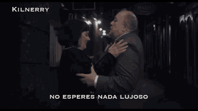a man and woman are dancing in front of a kilnerry sign