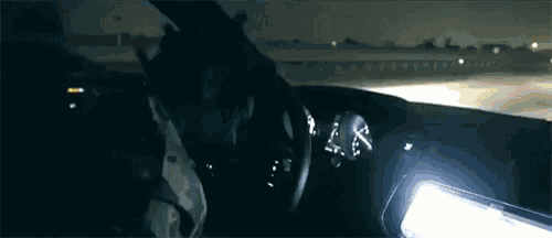 a man is driving a car at night and the dashboard has a clock on it that shows the time as 4:20