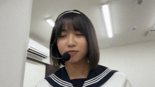 a girl in a sailor suit is wearing a headset and a microphone .