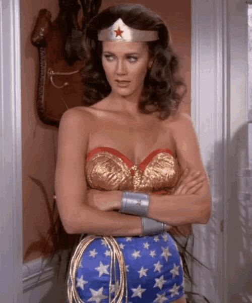 a woman dressed as wonder woman is standing with her arms crossed .