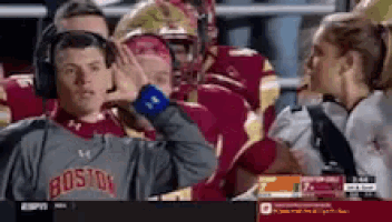 a man wearing a boston sweatshirt is covering his ears