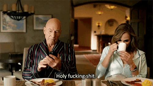 a man and a woman are sitting at a table with plates of food and one of them is saying holy fucking shit ..