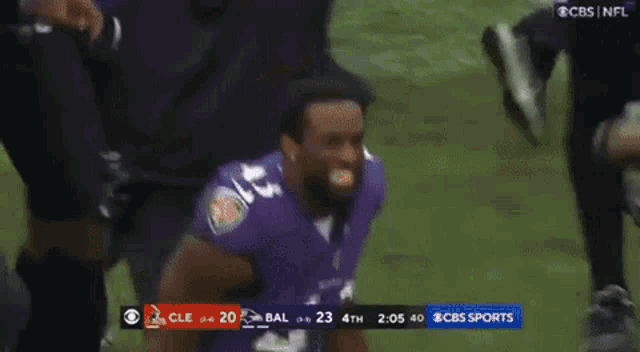 a football player in a purple jersey is kneeling down on the field .