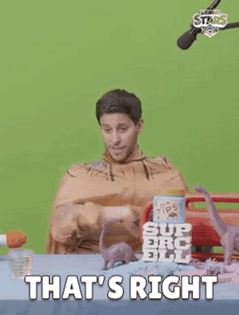 a man in a caveman costume is sitting at a table with dinosaurs and says `` that 's right ''