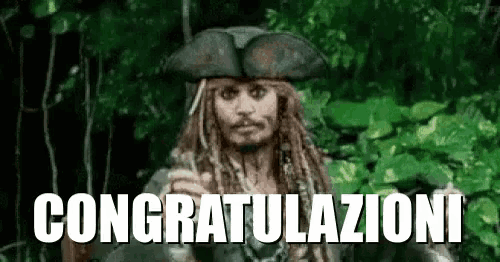 a man with dreadlocks and a pirate hat is standing in the woods holding a sword .