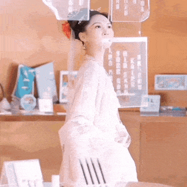 a woman in a white dress with a flower in her hair is standing in a room
