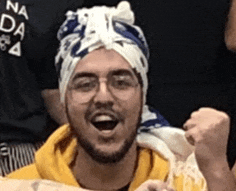 a man with a beard and glasses is wearing a turban and a yellow sweatshirt .