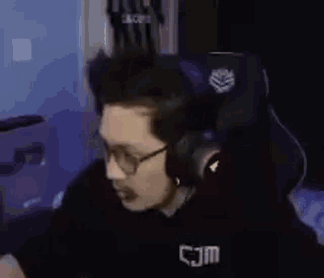 a man wearing glasses and headphones is sitting in a chair .