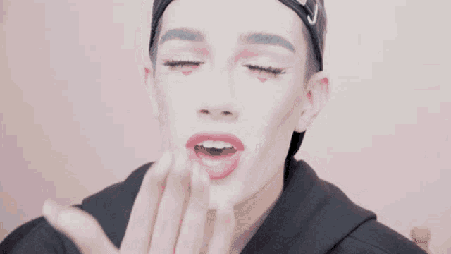a man wearing a black hat and a black hoodie has his tongue out