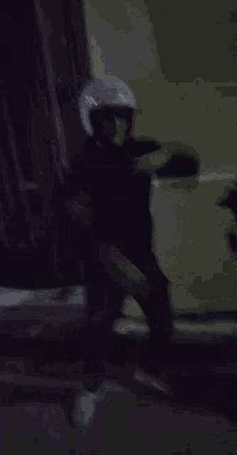 a person wearing a white helmet is dancing in the dark .