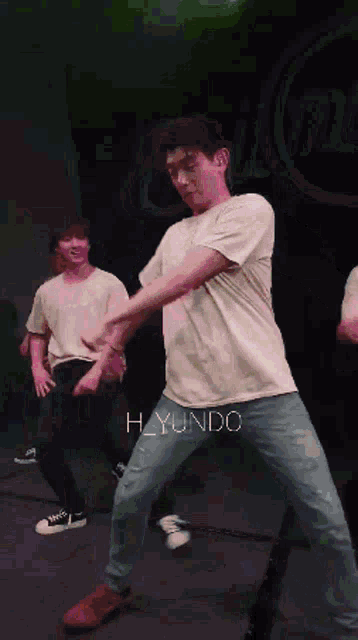 a man in a white t-shirt is dancing on a stage with the name h_yunda on the bottom