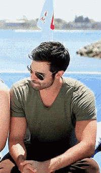 a man wearing sunglasses and a green shirt is sitting on a boat