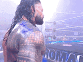 a man with a beard is standing in front of a wrestling ring in a stadium .
