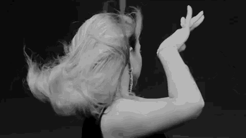 a woman is dancing on a pole with her hair blowing in the wind .