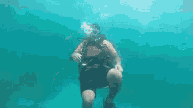a man is swimming underwater in the ocean wearing a scuba gear .