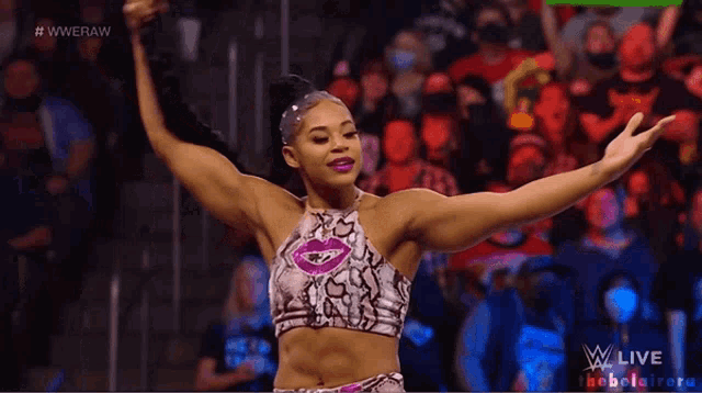 a female wrestler stands in front of a crowd with her arms outstretched and the words #wweraw behind her