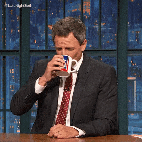 a man in a suit and tie holds a pepsi mug