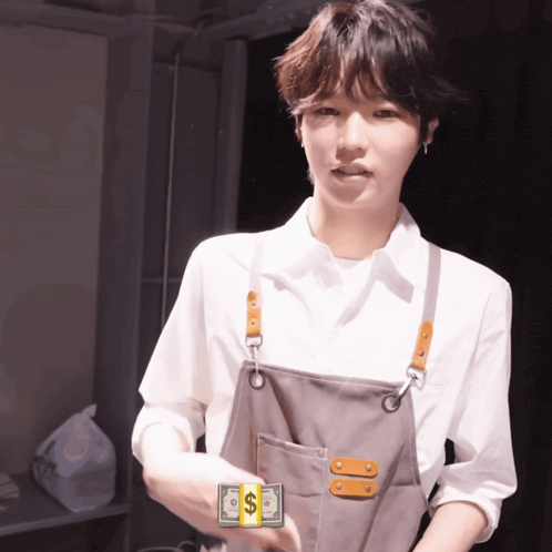 a man in an apron is holding a stack of dollar bills