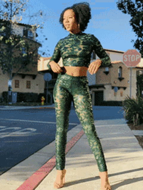 a woman standing on a sidewalk with a stop sign in the background