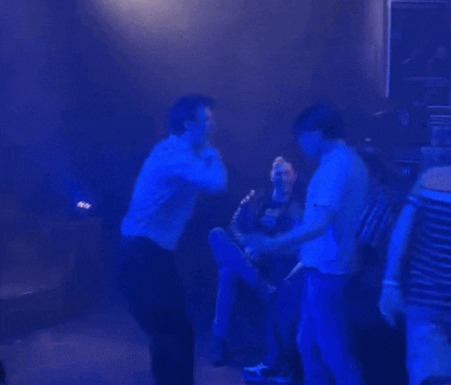 a group of people are dancing in a dark room with a sign that says ' a ' on it