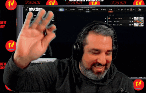 a man wearing headphones is waving in front of a screen that says warzone on it