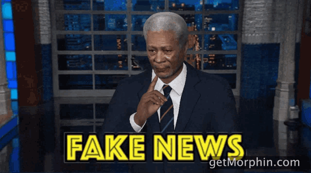 a man in a suit and tie waving in front of fake news