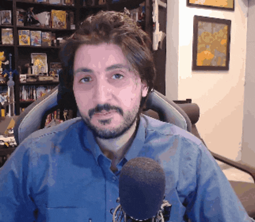 a man with a beard is sitting in a chair with a microphone in front of him