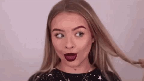 a woman with purple lipstick on her lips is making a funny face while holding her hair .